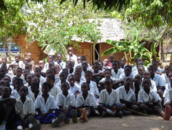More Students in Tanzania visited by the BFA Delegation with mud school buildings in the backround.